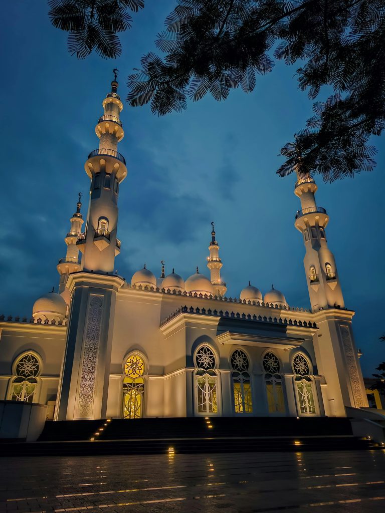 Beautifully illuminated mosque in Jawa Barat, Indonesia, captured at twilight with intricate Islamic architecture.