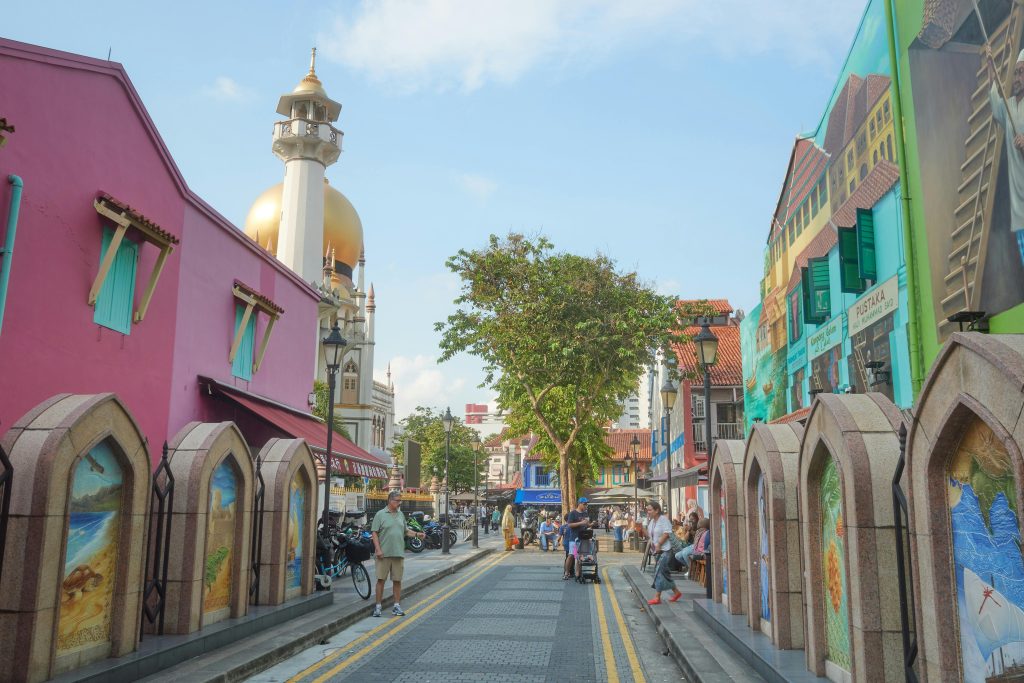Colorful street scene in Kampong Glam, Singapore, featuring the iconic Sultan Mosque and bustling pedestrian activity.