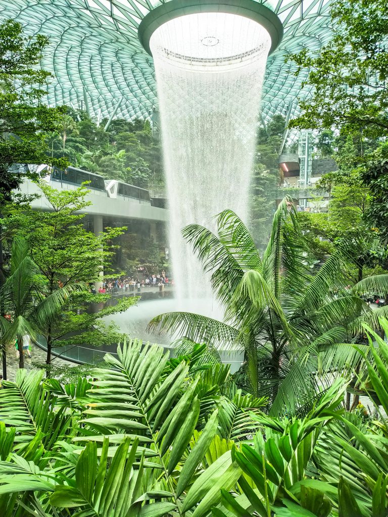Explore the stunning indoor Rain Vortex waterfall surrounded by lush greenery at Jewel Changi Airport, Singapore.