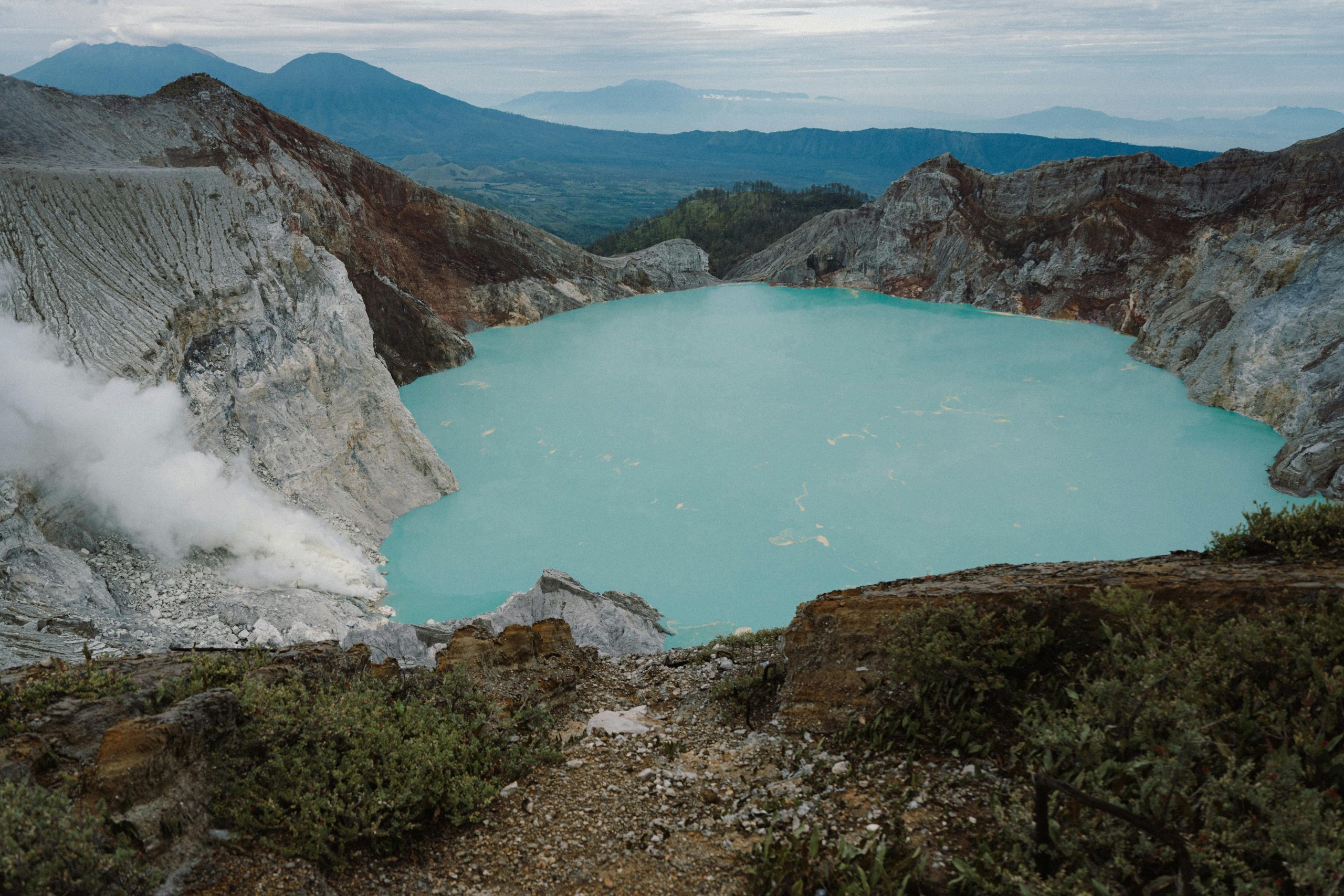 Breathtaking view of the Ijen Crater with turquoise lake and rugged volcanic landscape.