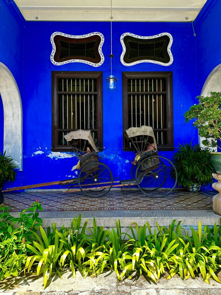 Two vintage rickshaws in front of the iconic Blue Mansion, George Town, Penang.